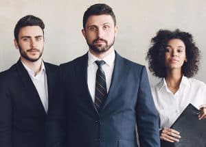 Three business professionals standing and looking in the camera