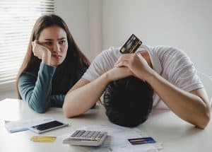 Stressed young couples about their finances with a calculator, credit cards, and bills placed on the table
