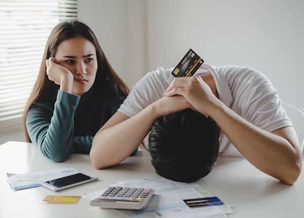 Stressed young couples about their finances with a calculator, credit cards, and bills placed on the table