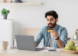 A young man with beard making an online payment from his laptop